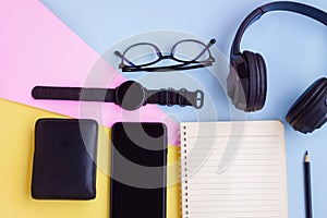 Smartphone,Smartwatch,Black Headphone,Black Wallet,Eyeglasses,Notebook and Black pencil on pink,blue and yellow background