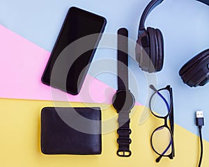 Smartphone,Smartwatch,Black Headphone,Black Wallet,USB cable and Eyeglasses on pink,blue and yellow background