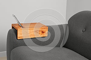 Smartphone on sofa with wooden armrest table in room. Interior element