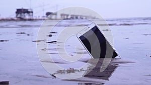 Smartphone stuck in the sand of the sea