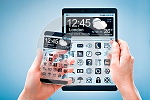 Smartphone and tablet with transparent screen in human hands.