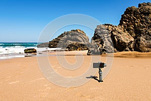 Smartphone takenig photo of Rocky stone on beach at sunny day, Atlantic ocean coast