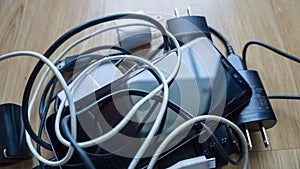 Smartphone tangled in differnt electronics cables chargers usb and black and white wires