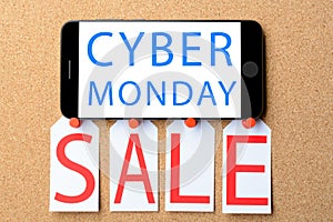 Smartphone with text on the screen CYBER MONDAY. Sale tags on a cork board