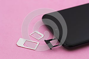 Smartphone with tray for SIM cards open on a pink table