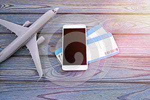 Smartphone, two plane tickets on a wooden background.