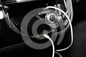 Smartphone with USB charging cable in modern car