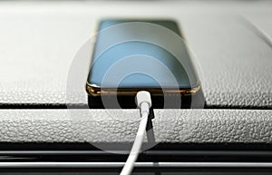 Smartphone with USB charging cable in modern car, closeup