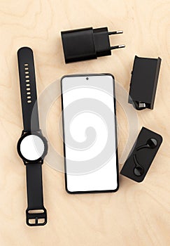 Smartphone and watch on a wooden table with a white screen.