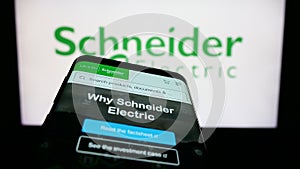 Smartphone with webpage of French company Schneider Electric SE on screen in front of business logo.