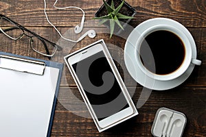 Smartphone white and a cup with coffee glasses and a blank on a brown wooden table. view from above