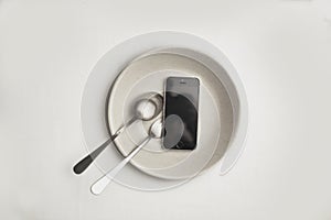 Smartphone on a white plate with fork and knife. Food delivery concept, top view, copy space. white background high key photo