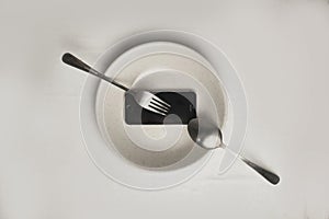 Smartphone on a white plate with fork and knife. Food delivery concept, top view, copy space. white background high key photo