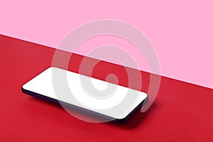 Smartphone with white screen on red and pink background, copy space