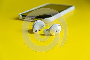 Smartphone white wireless headphones on a bright yellow background