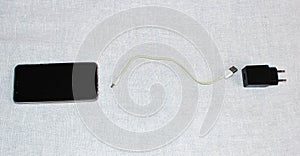 Smartphone, wire, charger on a light background separately