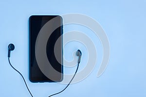 Smartphone and Wired earphones on Blue background