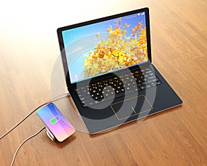 Smartphone on a wireless charging pad. The pad connected to a laptop computer