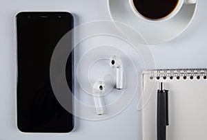 Smartphone, wireless earphones,  coffee and accessories on white  background