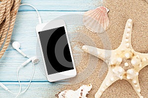 Smartphone on wood and sea sand with starfish and shells