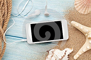 Smartphone on wood and sea sand with starfish and shells