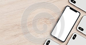 Smartphones like iPhone X mockup banner with copyspace flat lay top view lying on wooden office desk