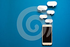 Smartphones with paper speech bubbles on blue background. Communication concept.