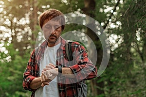 Smartwatch on male hiker hand while hiking in the woods