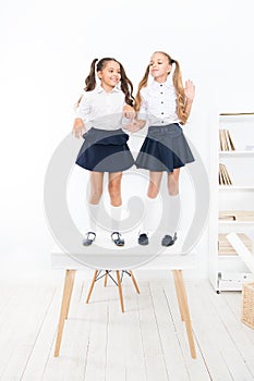 Smarty girls. Little school girls standing on desk in classroom. Small girls with long hair tails wearing fashion school