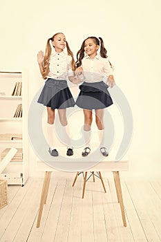 Smarty girls. Little school girls standing on desk in classroom. Small girls with long hair tails wearing fashion school