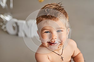 Smash cake party. Little cheerful birthday boy with first cake. Happy infant baby celebrating his first birthday. Decoration and