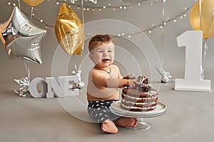 Smash cake party. Little cheerful birthday boy with first cake. Happy infant baby celebrating his first birthday. Decoration and