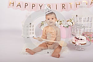 Smash cake party. Little cheerful birthday girl with first cake. Happy infant baby celebrating his first birthday. Decoration and