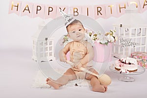 Smash cake party. Little cheerful birthday girl with first cake. Happy infant baby celebrating his first birthday. Decoration and