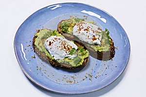 Smashed avocado on whole grain toast bread with poached organic eggs on a serving plate