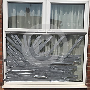 A Smashed Window Repaired with Silver Tape After An Attempted Burglary