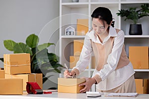 SME business entrepreneurs small in asia Writing shipping information on a cardboard box in my home office. Small