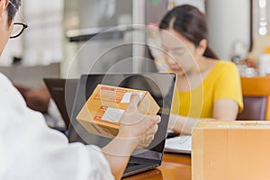 SME businessman holding paecel box with open labtop on table.