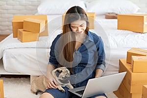 SME entrepreneur of Young women working with laptop for Online shopping at home with her dog pug breed