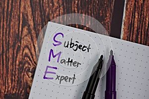 SME - Subject Matter Expert write on a book isolated on office desk