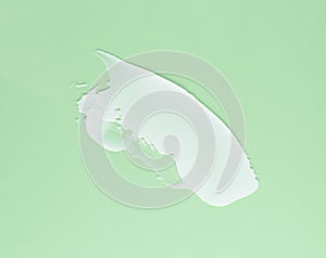 The Smear of white cream for face and body on a green background