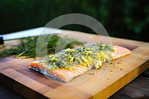 smearing herb garlic butter on cedar plank smoked salmon