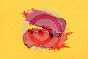 Smears of bright lipsticks on yellow background, top view