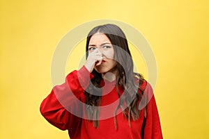 Smell bad. Young lady makes disgusts the smell isolate on yellow background. photo