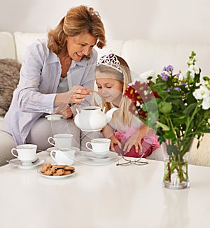 That smells really good granny. a grandmother and her granddaughter enjoying a tea party together.