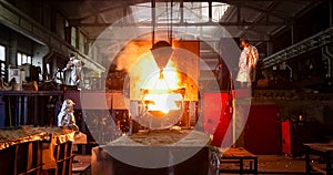 Smelting metal in a metallurgical plant. Liquid iron from metal ladle pouring in castings