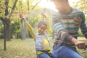 Smile African American father driving his little girl on bike t