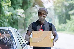 Smile african male postal delivery courier man in front of car delivering package