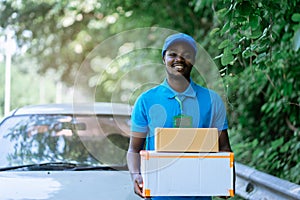 Smile african man postal delivery courier man in front of car delivering package