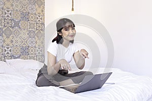 Smile asian beautiful girl is pointing the laptop in the bed. Work from home concept